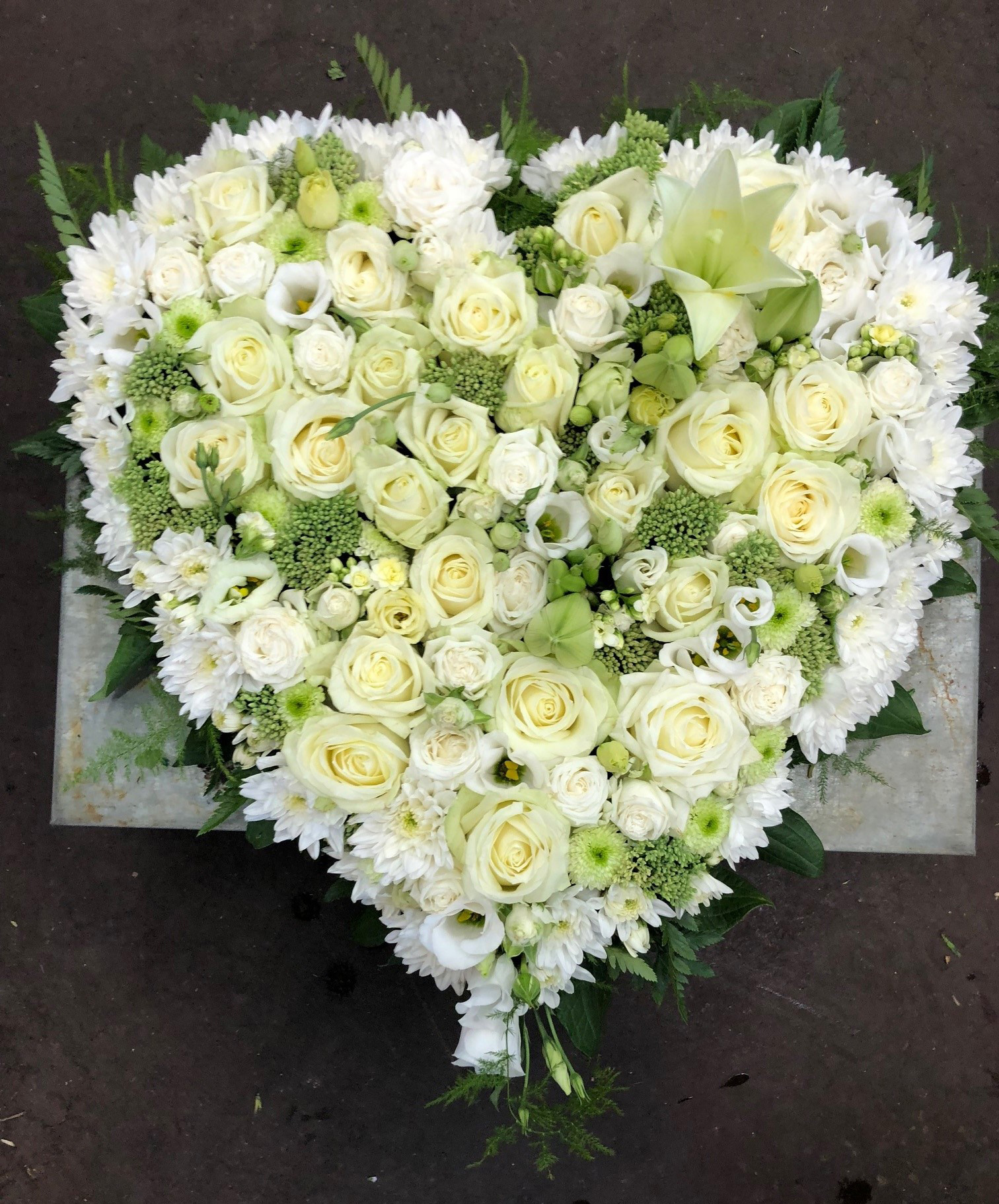 Begravelseshjerte stukket med hvide blomster. 