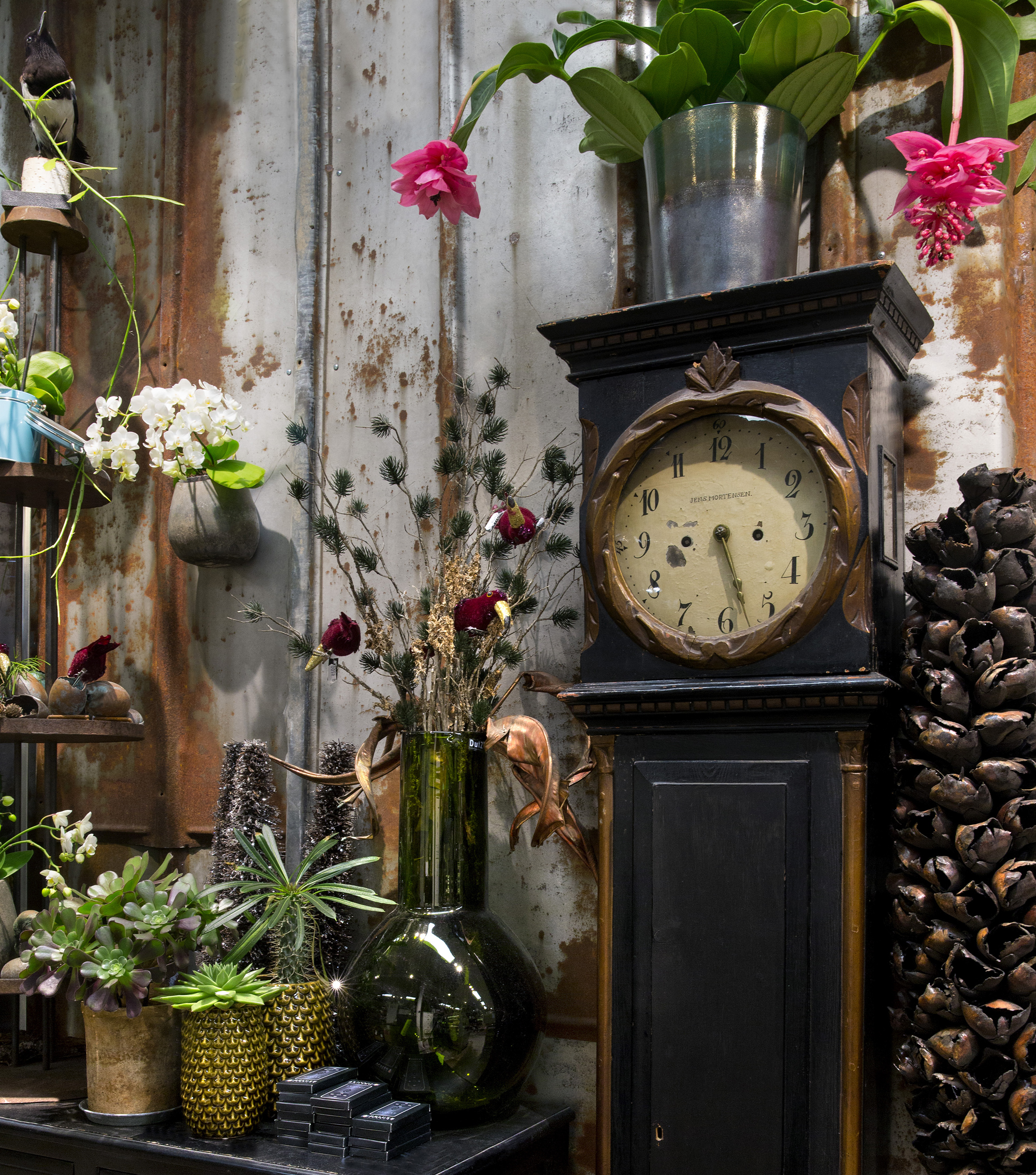 Bornholmerur og forskellige pyntegenstande står foran rusten væg