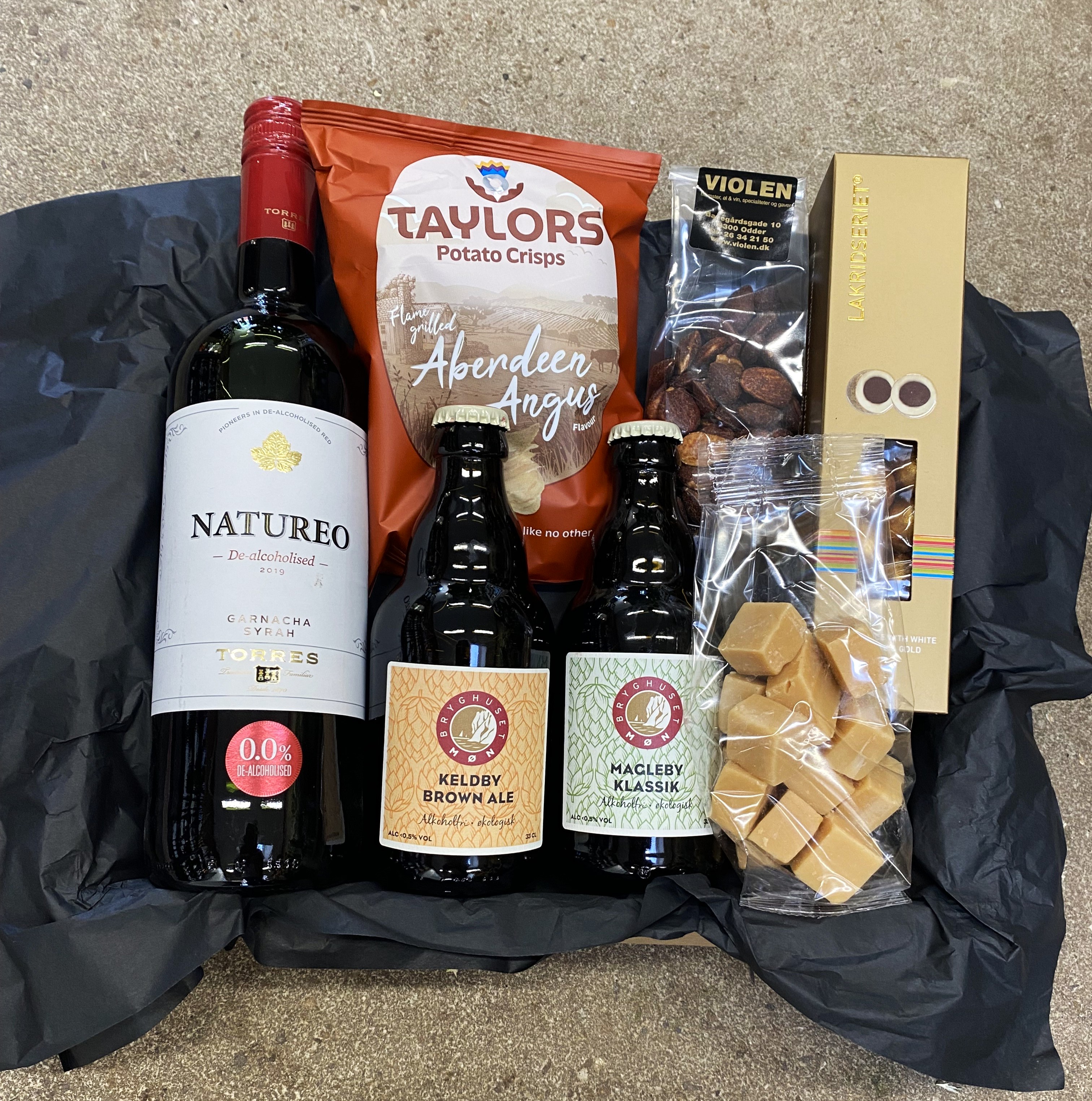 Gavekurv med alkoholfri vin, øl og specialiteter af chips, karameller og chokolade. 